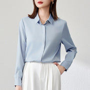 Graceful satin top in light blue with long shirt sleeves and button details, styled in urban fashion.