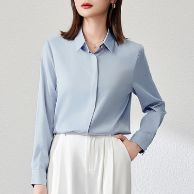Graceful satin top in light blue with long shirt sleeves and button details, styled in urban fashion.